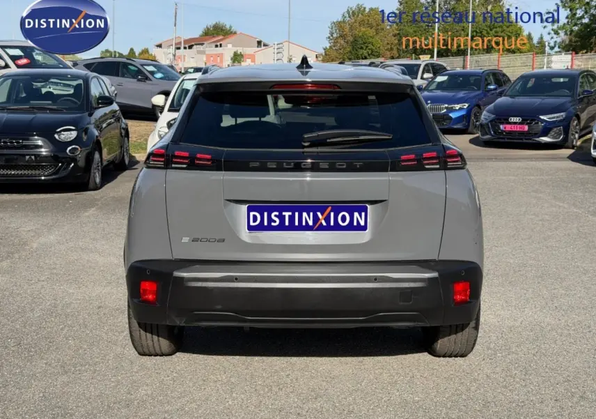 Vue arrière d'un Peugeot e-2008 gris Artense 2025 avec feux LED et lunette arrière surteintée sur parking.