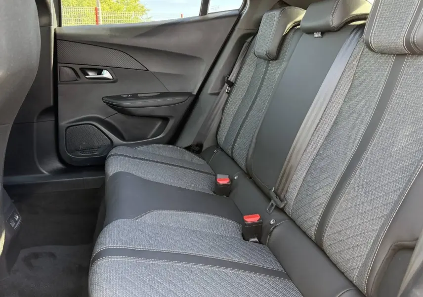 Vue latérale droite de la banquette arrière en tissu gris et cuir noir du Peugeot e-2008 2025, avec ceintures de sécurité visibles.