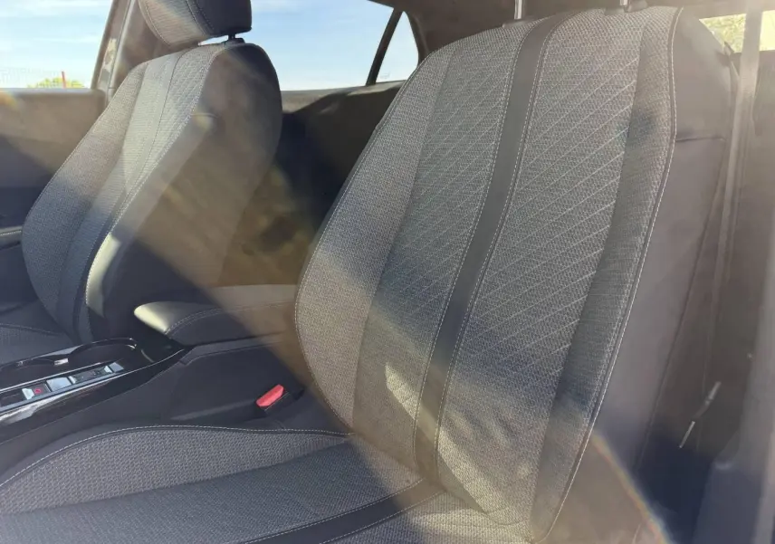 Gros plan sur les sièges avant gris tissu CASUAL LOMSA embossé de la Peugeot e-2008 2025, lumière naturelle traversante.
