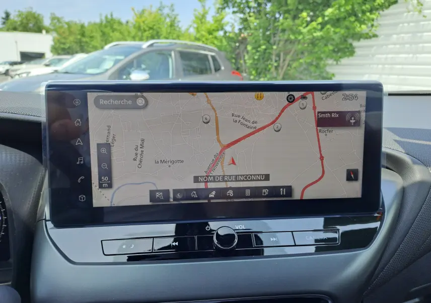 Écran tactile central du Nissan Juke Hybrid 2025 affichant la navigation avec carte et commandes audio intégrées.