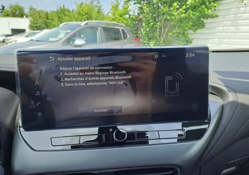 Vue intérieure du tableau de bord du Nissan Juke Hybrid 2025 avec écran tactile affichant le menu Bluetooth.
