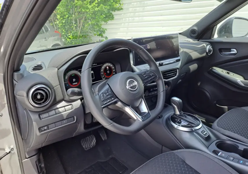 Intérieur noir du Nissan Juke Hybrid 143 N-Connecta 2025, vue côté conducteur sur volant et console centrale avec écran tactile.