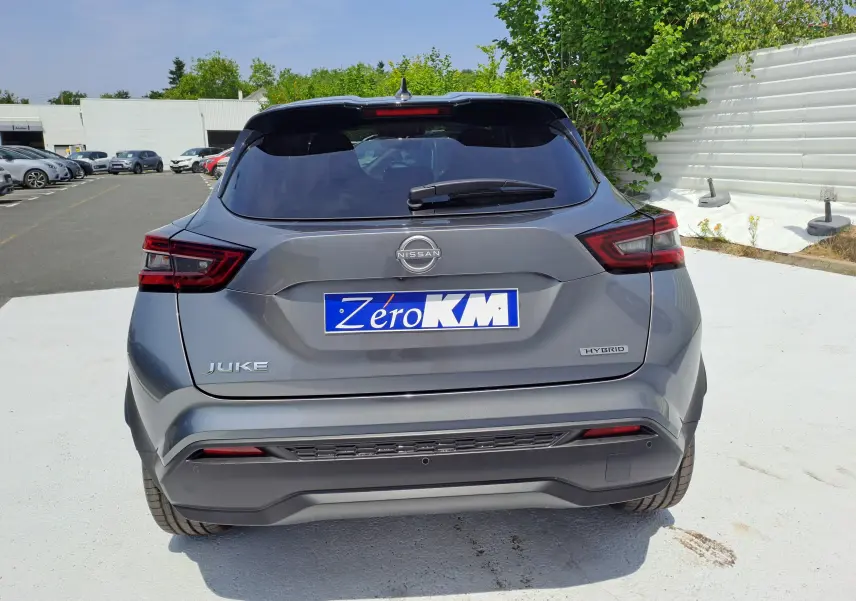 Vue arrière d'un Nissan Juke Hybrid 143 N-Connecta gris squale avec feux arrière LED et logo Nissan visible.