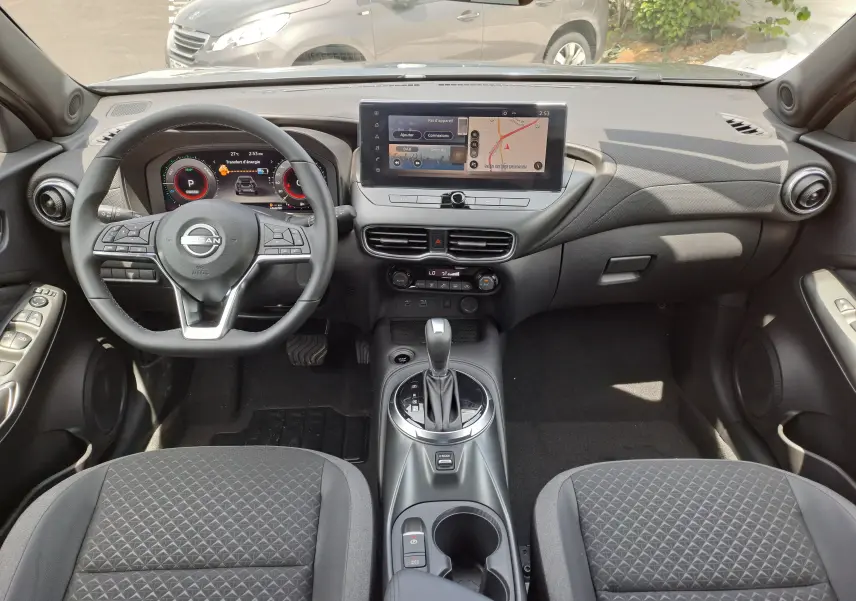 Vue intérieure avant du Nissan Juke Hybrid 143 N-Connecta 2025 avec tableau de bord numérique et écran tactile central.