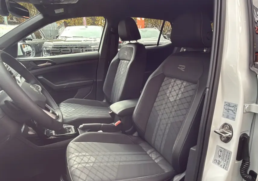 Intérieur du Volkswagen T-Cross TSI 116 DSG7 R-Line blanc, vue côté conducteur sur les sièges avant en tissu avec logo R.