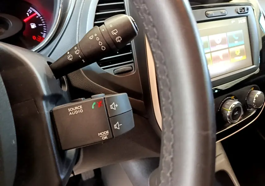 Vue rapprochée du volant noir et des commandes audio sur le côté gauche du tableau de bord du Renault Captur Business 2018.