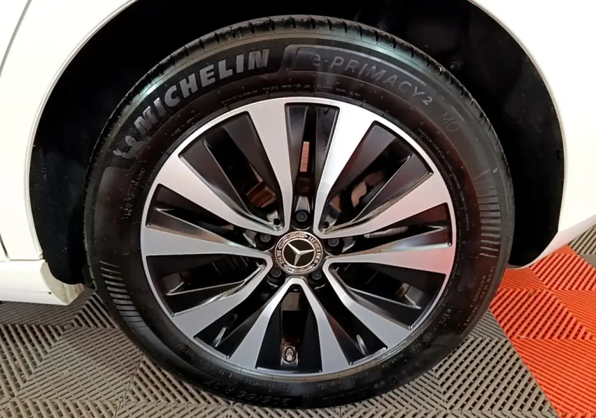 Gros plan sur la roue avant droite d’une Mercedes Classe A blanche, jante alliage bicolore et pneu Michelin.