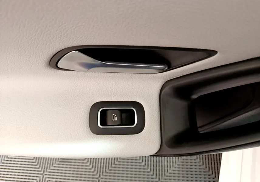 Gros plan sur la poignée intérieure et le bouton de verrouillage de porte, garniture cuir blanc de la Mercedes Classe A.