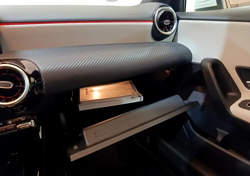 Vue intérieure côté passager de la Mercedes Classe A 250 e Business Line 2020, boîte à gants ouverte et tableau de bord noir et blanc.