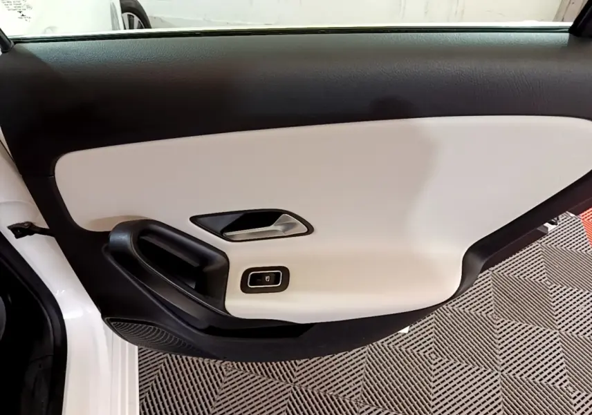 Vue intérieure de la porte avant gauche blanche de la Mercedes Classe A Berline A 250 e avec garniture bicolore noire et beige.