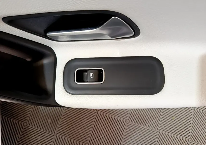 Gros plan sur la commande de lève-vitre électrique sur la porte intérieure blanche d'une Mercedes Classe A Berline.