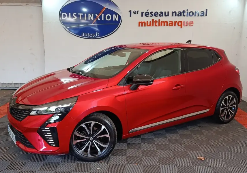 Renault Clio Techno TCe 90 rouge vue 3/4 avant droit, jantes alliage et feux LED distinctifs visibles.