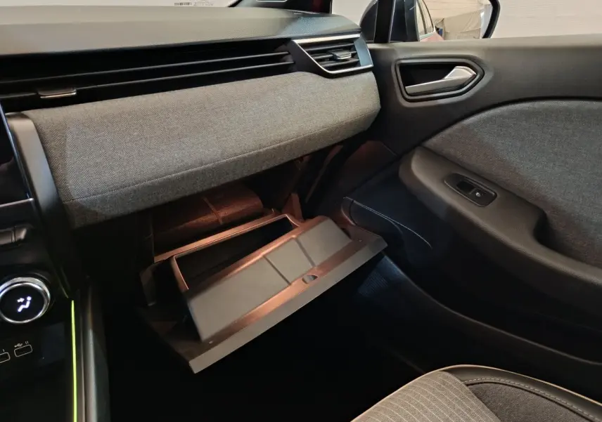 Intérieur de la Renault Clio Techno TCe 90 2024, vue côté passager avec boîte à gants ouverte et tissus gris.