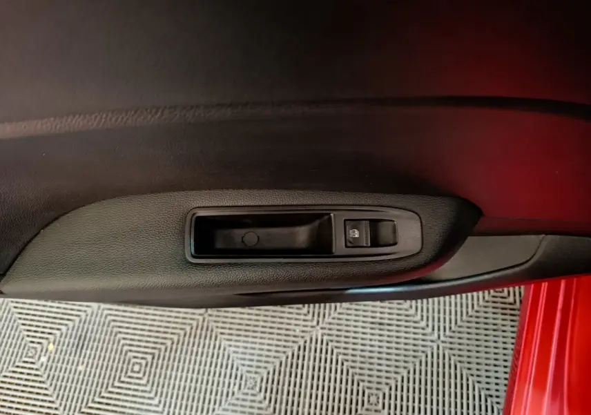 Poignée de porte intérieure côté gauche en plastique noir sur Renault Clio Techno TCe 90 rouge, vue rapprochée.