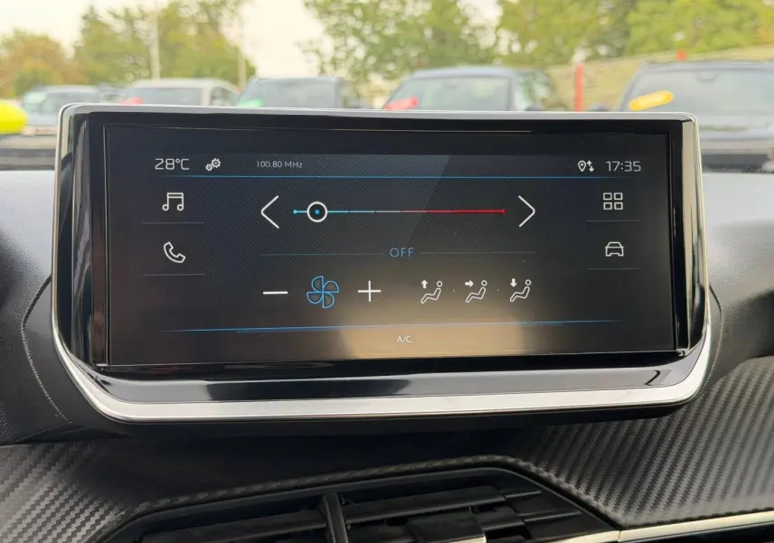 Vue intérieure centrée sur l'écran tactile multifonction du tableau de bord de la Peugeot 208 blanc Okénite.