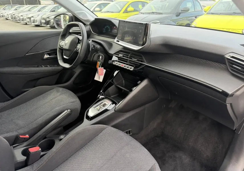 Vue intérieure côté conducteur de la Peugeot 208 1.2 Hybrid 110ch Style 2025 avec tableau de bord moderne et sièges tissu gris.
