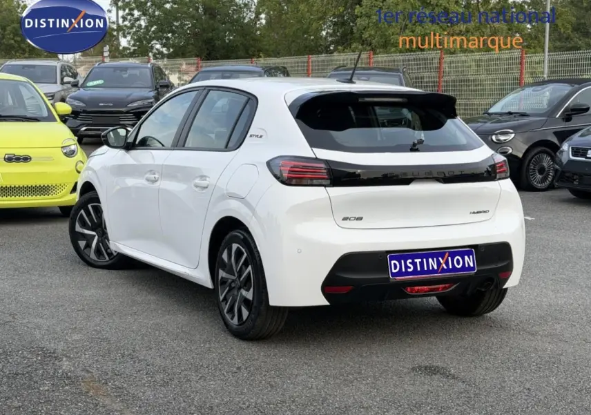 Vue 3/4 arrière droite d'une Peugeot 208 blanche Okénite avec toit noir et jantes distinctives en concession.