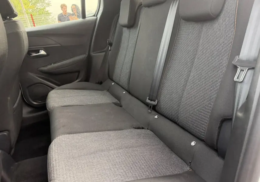 Vue intérieure côté droit de la banquette arrière tissu gris avec surpiqûres orange dans une Peugeot 208 blanche.