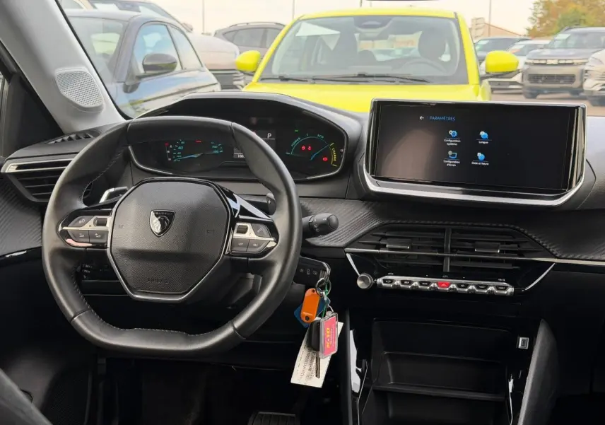 Vue intérieure centrée sur le volant Peugeot 208 blanc Okénite, avec écran tactile et tableau de bord numérique.