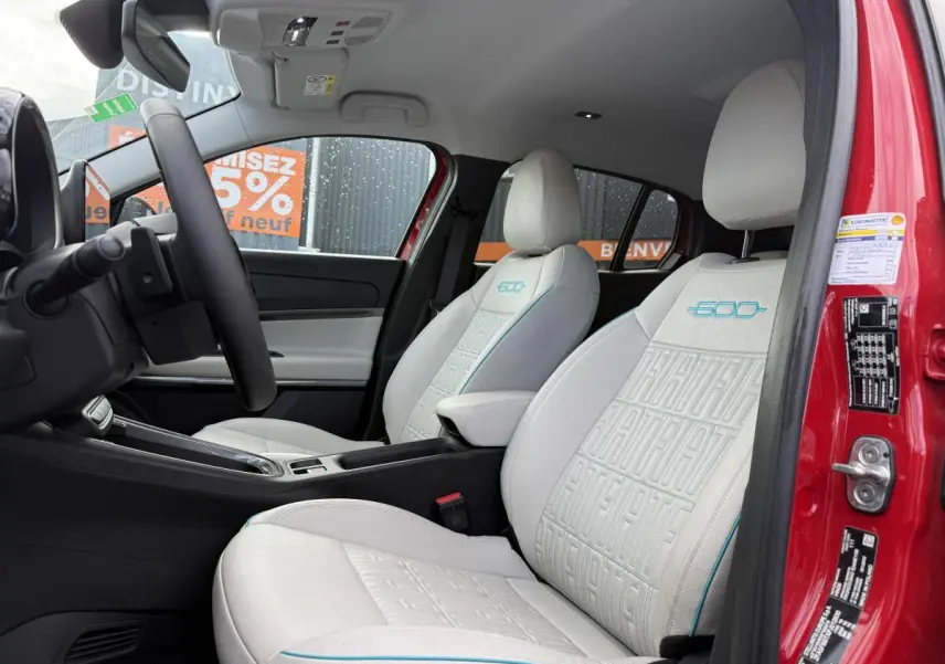 Intérieur de la FIAT 600 La Prima rouge, vue côté conducteur, sièges ivoire avec monogrammes bleus 600 et ECO.