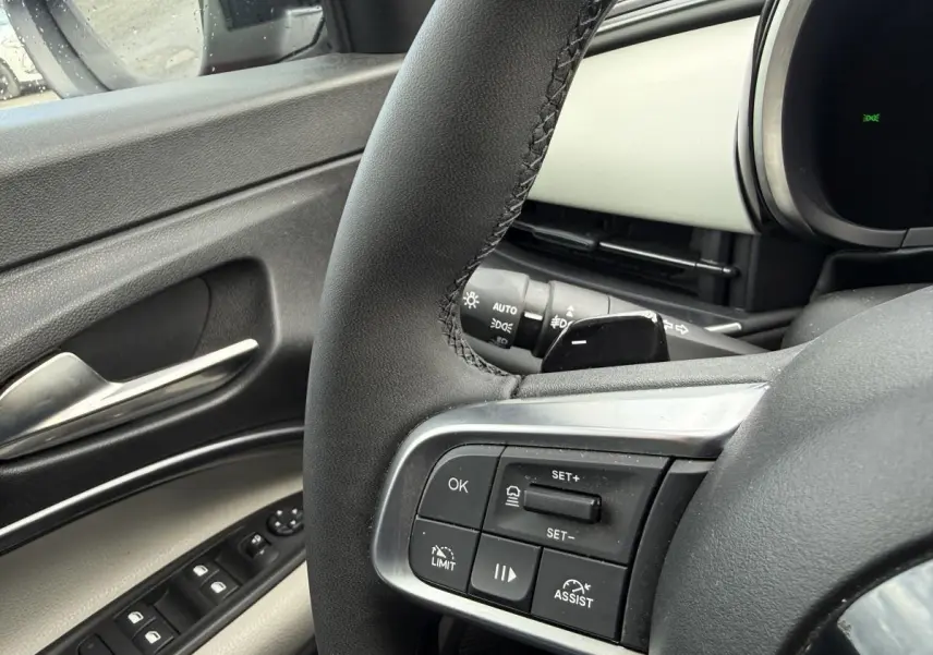 Gros plan sur le volant côté gauche et la portière ivoire de la FIAT 600 La Prima 2024, avec commandes intégrées.