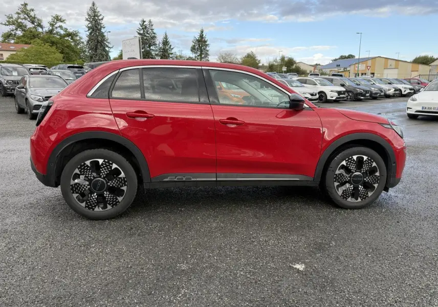 Vue latérale gauche d'une FIAT 600 1.2 Hybrid rouge avec jantes alliage noires et logo 600 sur la porte.