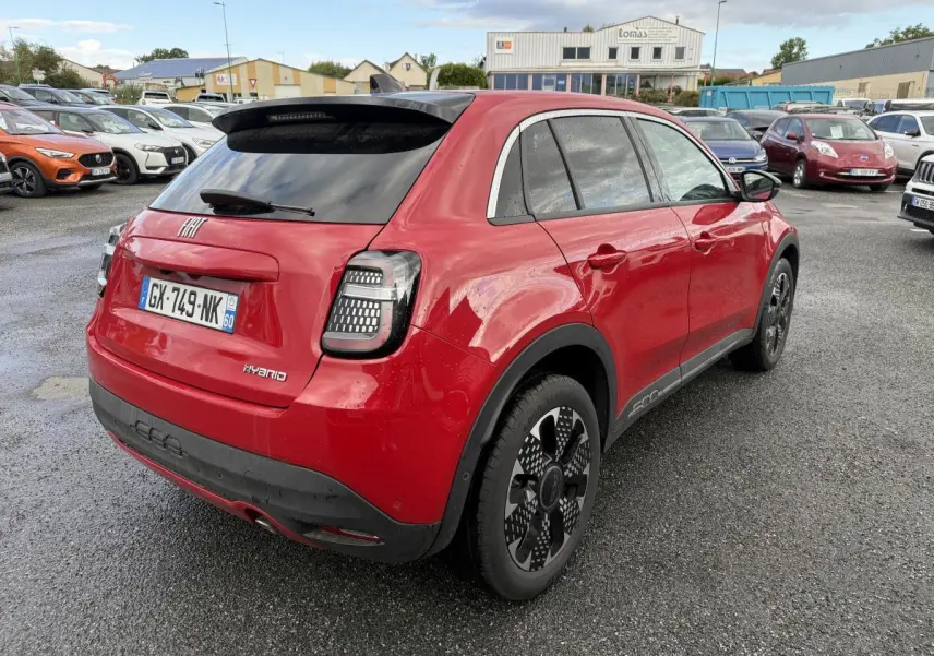 Vue 3/4 arrière droite d'une FIAT 600 hybride rouge avec jantes alliage 18'' et vitres arrière surteintées.