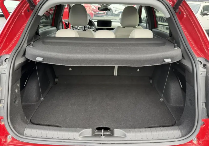 Coffre ouvert vu de l'arrière d'une FIAT 600 rouge, avec banquette arrière ivoire et cache-bagages déployé.