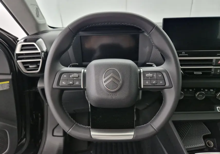Vue frontale du volant cuir noir de la Citroën C4 1.2 Hybrid 136 Business Edition avec commandes intégrées et tableau de bord digital.