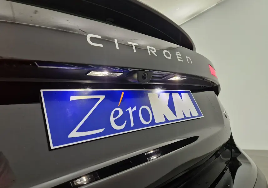 Gros plan sur l'arrière noir brillant d'une Citroën C4 2025 avec caméra de recul et plaque "Zéro KM" bleue.