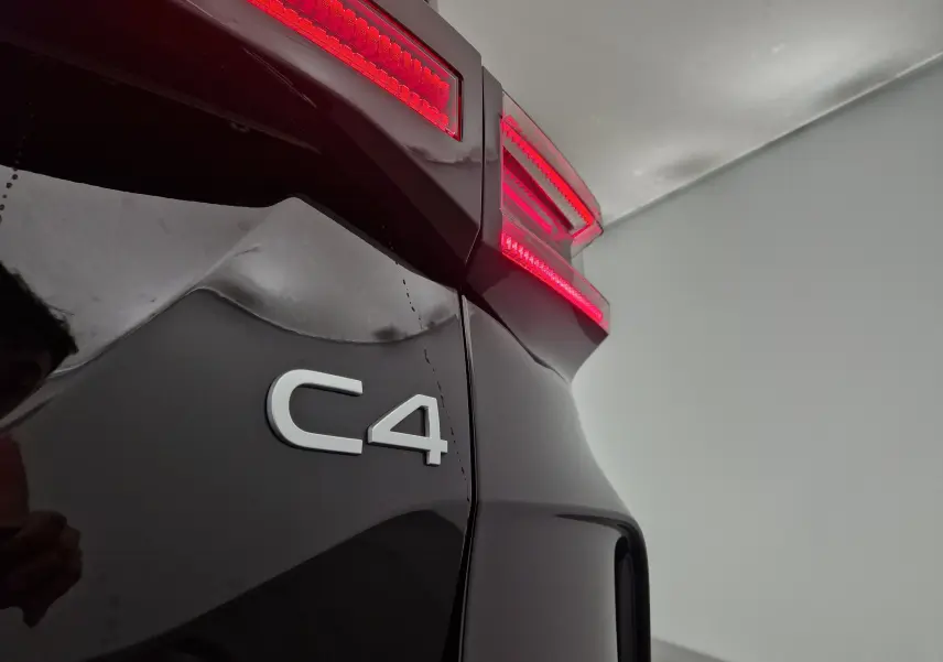Gros plan sur le feu arrière droit rouge et le logo C4 du coffre d'une Citroën C4 noire 2025.
