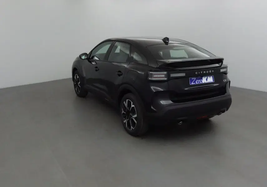 Citroën C4 noir vue 3/4 arrière droit en intérieur, avec jantes noires et feux arrière LED distinctifs.