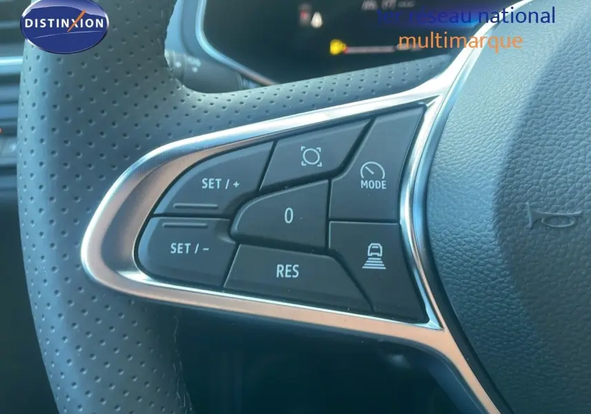 Gros plan sur les commandes du volant perforé noir du Renault Captur E-Tech Hybrid 2025, avec boutons de régulateur et mode.