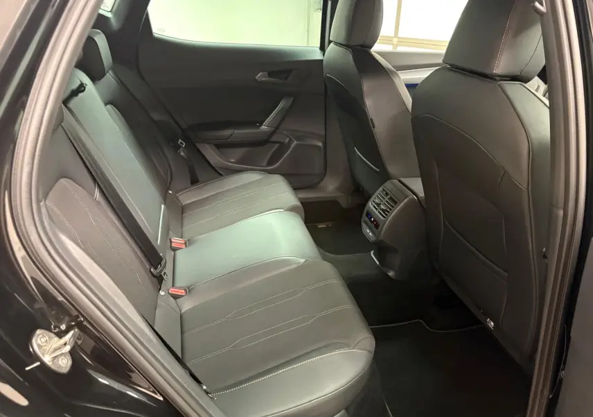 Vue intérieure arrière côté gauche de la CUPRA Formentor 1.5 TSI 2024 en Noir Minuit, sièges cuir et aérateurs centraux visibles.