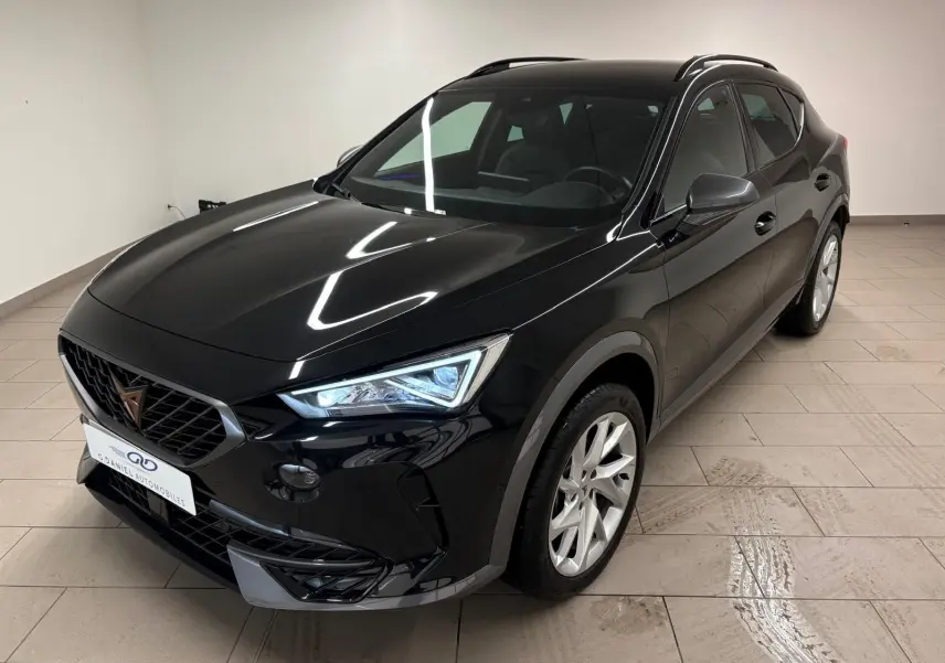 CUPRA Formentor noir minuit en 3/4 avant droit, avec phares allumés et jantes argentées visibles en intérieur clair.