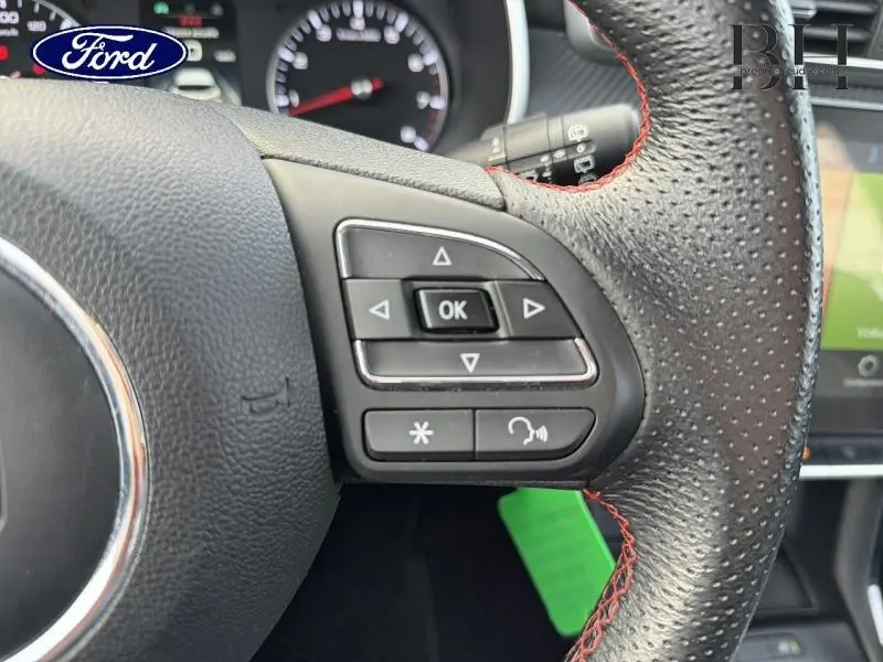 Gros plan sur les commandes au volant cuir perforé avec surpiqûres rouges du MG ZS Cosmic Silver 2022.