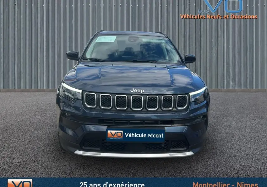 Vue avant d'un Jeep Compass bleu 2023 avec calandre distinctive et barres de toit visibles sur fond neutre.
