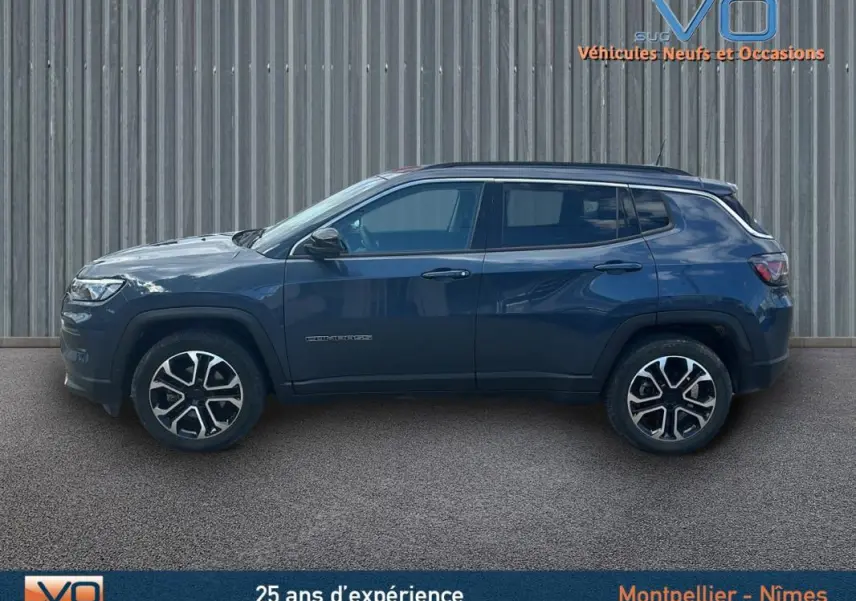 Vue de profil côté gauche d’un Jeep Compass bleu 2023 avec jantes 18 pouces et barres de toit visibles.