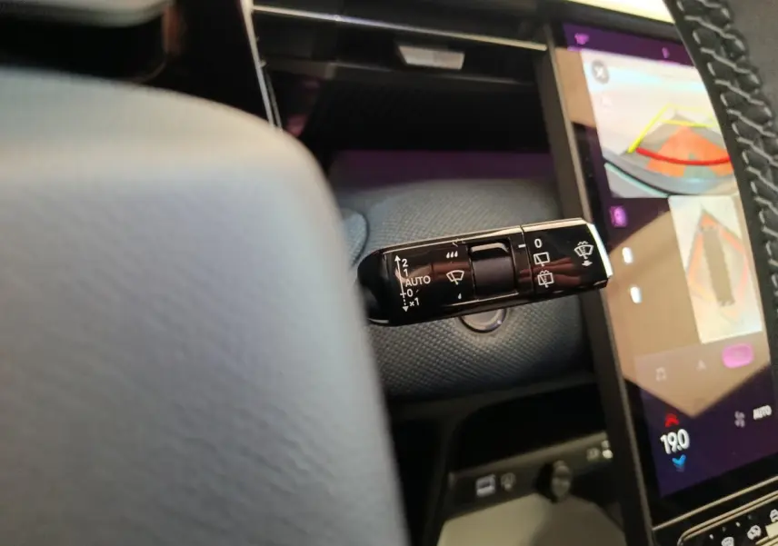 Gros plan sur la commande d’essuie-glace à gauche du volant dans l’habitacle du Citroën C5 hybride gris foncé.