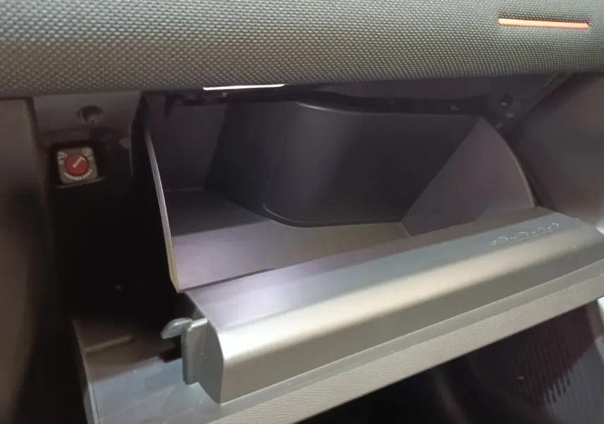 Gros plan sur la boîte à gants ouverte de la Citroën C5 Hybride 2026, intérieur noir mat et texture sobre.