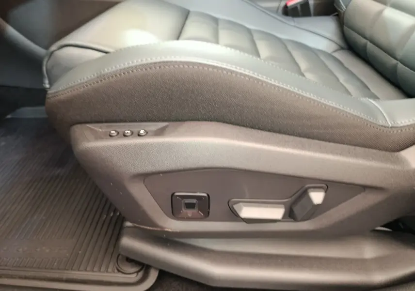 Gros plan sur les commandes de réglage électrique du siège avant gauche en cuir gris foncé du Citroën C5 hybride 2026.