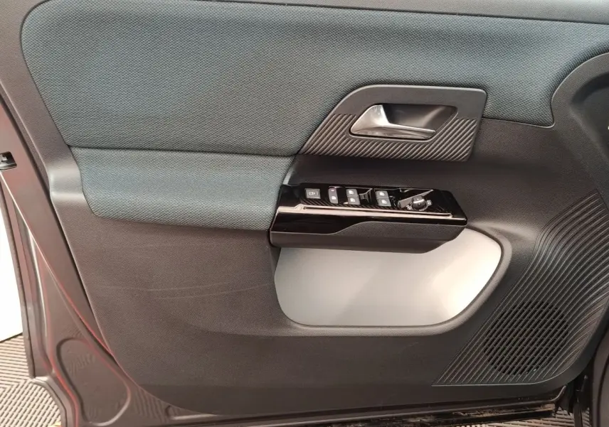 Détail de la porte avant gauche de la Citroën C5 hybride gris foncé, avec commandes de vitres et poignée intérieure.