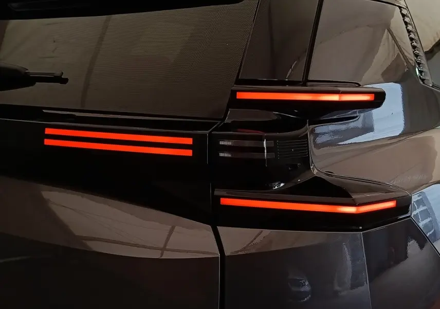 Gros plan sur le feu arrière droit rouge lumineux d'une Citroën C5 hybride gris foncé, finition 2026.