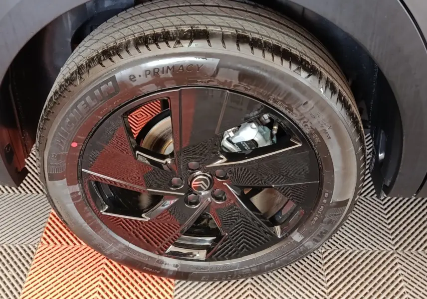 Gros plan sur la roue avant droite avec jante noire brillante et logo Citroën au centre, pneu Michelin e-Primacy.