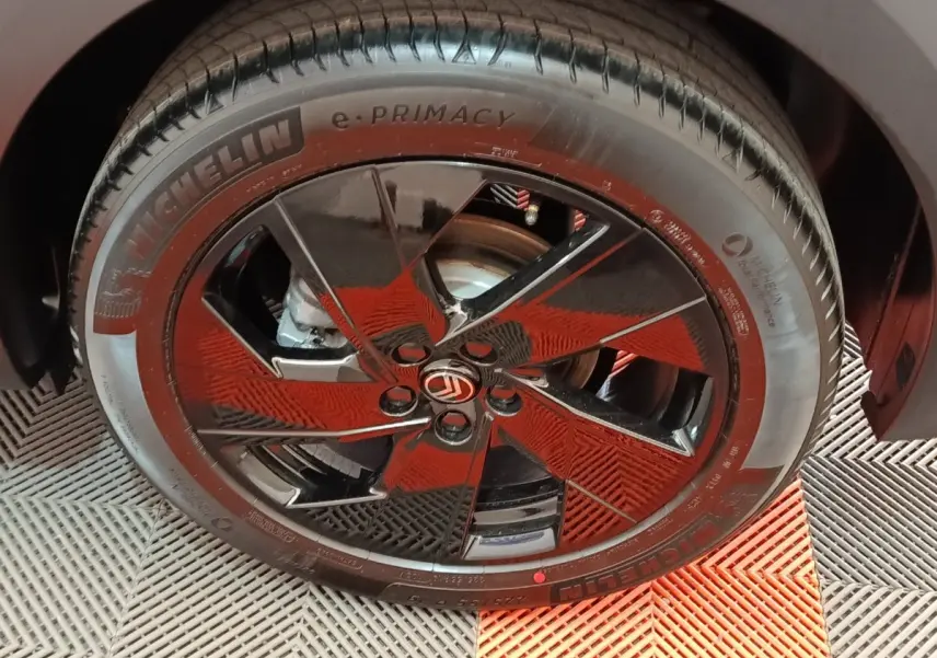 Gros plan sur la roue avant droite d’une Citroën C5 hybride gris foncé avec jante noire brillante et logo Citroën central.
