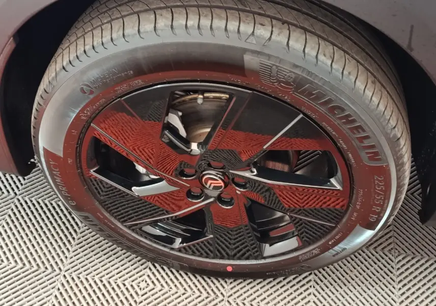 Gros plan sur la roue avant droite du Citroën C5 Hybride gris foncé avec jante noire brillante et logo Citroën central.
