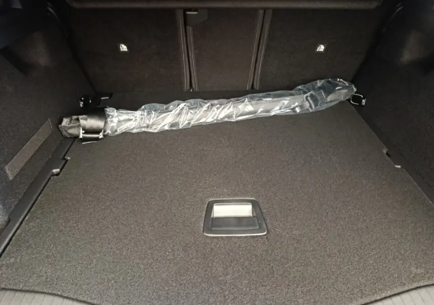 Coffre spacieux de Citroën C5 Hybride gris foncé vu de l’intérieur, avec protection et rangement intégré.