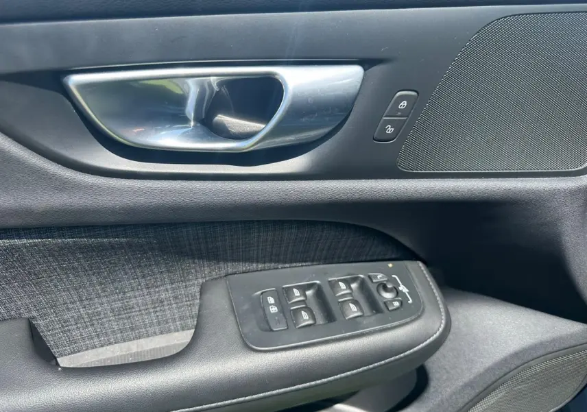 Poignée de porte intérieure côté gauche de Volvo S60 2024 en Thunder Grey avec commandes de vitres et verrouillage.
