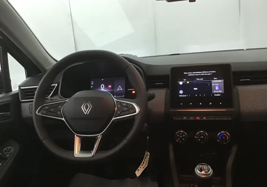 Vue intérieure centrée sur le volant Renault Clio V 2025 avec écran tactile et levier de vitesse manuel.