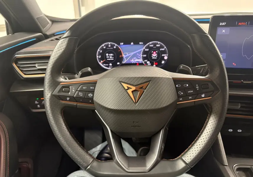 Vue rapprochée du volant en cuir perforé noir avec logo CUPRA cuivré et tableau de bord numérique du Formentor 2024.